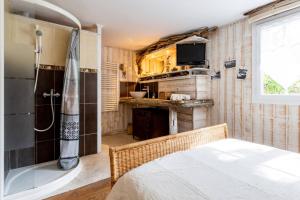 a bedroom with a shower and a bed and a television at La Cabane de Bébert - Marie en Lys in Cap-Ferret