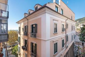 a pink building with black shutters and a balcony at Civico 32 in Salerno