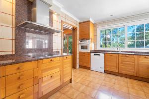 a large kitchen with wooden cabinets and a sink at Ilusion in Olocau