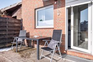 three chairs and a table in front of a brick building at Klein aber fein in Worpswede