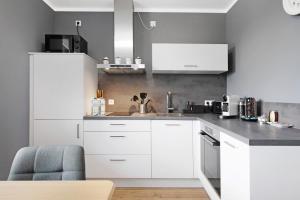 a kitchen with white cabinets and a blue chair at B5fewo in Bad Bellingen