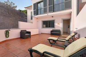 a patio with chairs and tables and a building at Moradia Casa Feliz in Santa Cruz