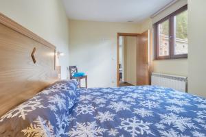 a bed with a blue blanket with snowflakes on it at Valle del Ibias - Segundo Izquierda in Cecos