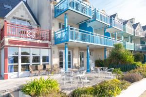 a building with blue balconies and tables and chairs at L' Eclose Cap Marine in Le Guilvinec