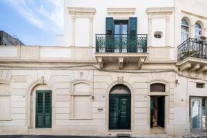 a white building with green doors and windows at Casa Pizzicchia in Muro Leccese