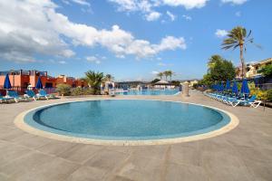 a swimming pool in a resort with chairs and palm trees at Meloneras 1 in Maspalomas
