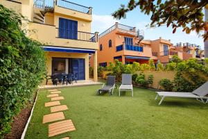a patio with chairs and a lawn in front of a building at Meloneras 1 in Maspalomas
