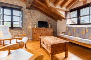 a living room with a table and a tv at Casa Rural Perullé in San Vicente de la Barquera
