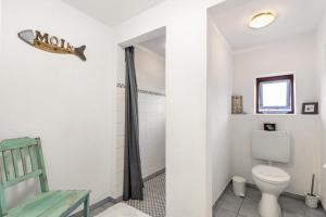 a bathroom with a toilet and a green chair at Wat'n Utkiek in Rodenäs +25 photos