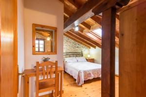 a bedroom with a bed and a table and a mirror at Casa Rural Perullé in San Vicente de la Barquera