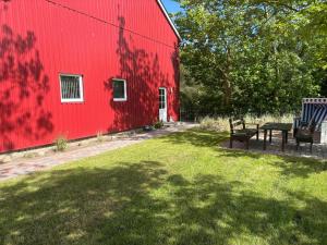 a red barn with a table and a bench next to it at Wat'n Utkiek in Rodenäs