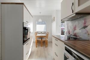 a kitchen with white cabinets and a table with a chair at Kleines Schweden in Hennstedt