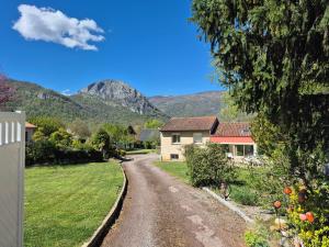 a house on a road with a mountain in the background at Gîtes le Clos des Pradals in Tarascon-sur-Ariège