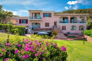 a large pink house with flowers in the yard at 6 Appartamento Molara in San Teodoro