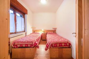 two beds in a room with red blankets at La pratolina piano terra in Castello di Fiemme