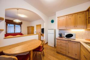 a kitchen with a wooden table and a dining room at La pratolina piano terra in Castello di Fiemme