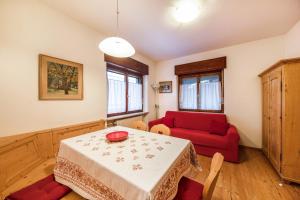a living room with a table and a red couch at La pratolina piano terra in Castello di Fiemme +8 photos