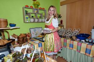 a woman holding a plate in front of a table at Simply Rooms in Velden am Wörthersee