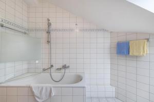 a white tiled bathroom with a tub and a shower at Fewo Brünnstein - Zimmer 65 in Oberaudorf +28 photos