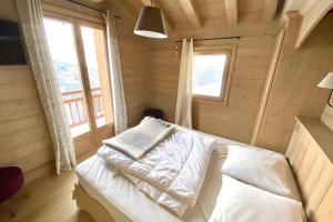 a bed in a wooden room with two windows at Les Craterelles 3 - 1650 in Courchevel