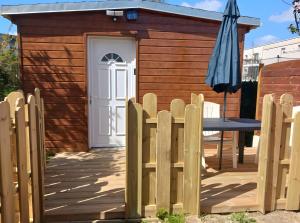 a small wooden shed with a table and an umbrella at Chalet proche dinard in Pleurtuit