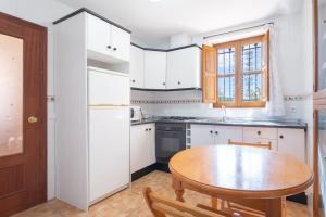 a kitchen with white cabinets and a wooden table at Casa del Practicant in Culla