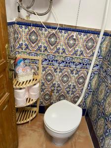 a bathroom with a toilet and a tile wall at Casa Nora in Iznate