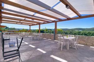 a patio with white tables and chairs and a stone wall at La Mignola - Casa Vacanze in Vieste