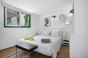 a bedroom with a white bed with a black stool at Piscina Climatizada in La Hidalga +24 photos