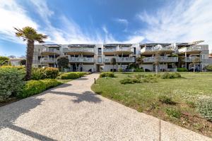 a large apartment building with a palm tree and a sidewalk at Résidence Le Rêve Apt 209 in La Tranche-sur-Mer
