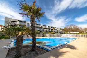 a swimming pool with palm trees in front of a building at Résidence Le Rêve Apt 209 in La Tranche-sur-Mer