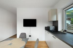 a kitchen with a table and a tv on the wall at Premium App Hofer Maria in Villabassa