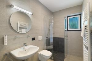 a bathroom with a sink and a toilet and a mirror at Premium App Hofer Maria in Villabassa +21 photos