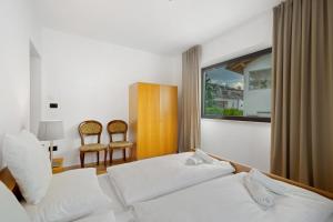 a bedroom with a bed and two chairs and a window at Premium App Hofer Maria in Villabassa