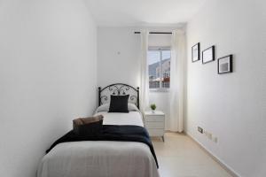 a white bedroom with a bed and a window at Apartamento Opuntia in La Orotava