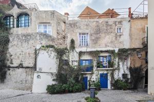an old stone building with blue doors and ivy at Navila Estudio en la piscina in Ibiza Town