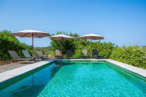 a swimming pool with chairs and umbrellas at Els Clepes in Son Servera