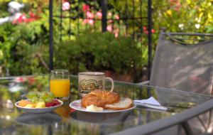 a glass table with a plate of food and a cup of orange juice at Noe's Nest Bed and Breakfast in San Francisco
