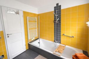 a bathroom with a tub and yellow tiles at Huus ant Kornfeld Erdgeschoss in Osteel +22 photos