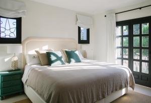 a white bedroom with a white bed with blue pillows at Villa Torre in Jávea