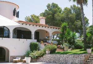 a white house with a stone wall and trees at Villa Torre in Jávea