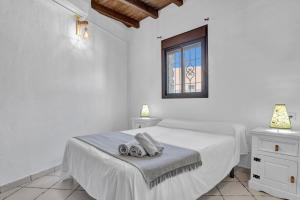 a white bedroom with a bed and a window at Casas al Alba in Zahora +19 photos