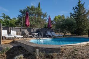 a pool with chairs and umbrellas in a yard at Gîte Chêne ou Murier in Les Vans