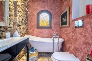 a bathroom with a tub and a toilet and a window at Villa Sa Pintadera private pool in Stintino