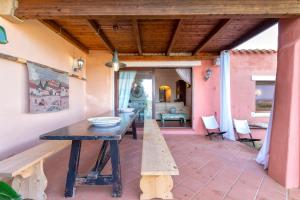 a patio with a wooden table and a bench at Villa Sa Pintadera private pool in Stintino +15 photos