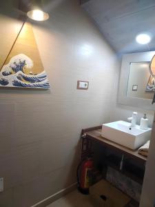 a bathroom with a sink and a painting of a wave at Más Quimera in Gilgarcía +19 photos