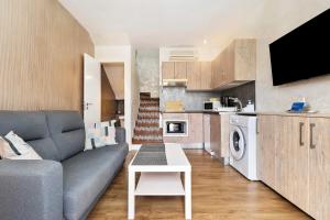 a living room with a gray couch and a kitchen at Bungalow Green Oasis in San Bartolomé