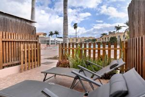 a patio with chairs and a fence and palm trees at Bungalow Green Oasis in San Bartolomé