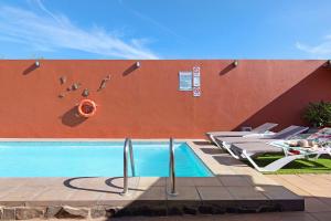 a swimming pool with lounge chairs next to a wall at La Casita de Vals in Valsequillo
