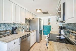 a kitchen with white cabinets and a sink at pink peacock in Holmes Beach